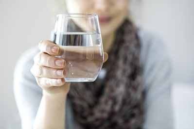 young woman drinking water out of a glass