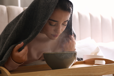 woman inhaling steam from a bowl